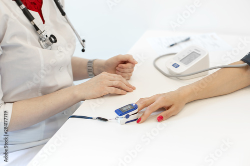 The doctor puts on the sensor measuring the pulse and oxygen in the blood on the patient's finger