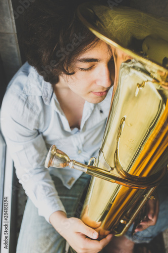 Teenage boy with eyes closed holding his tuba