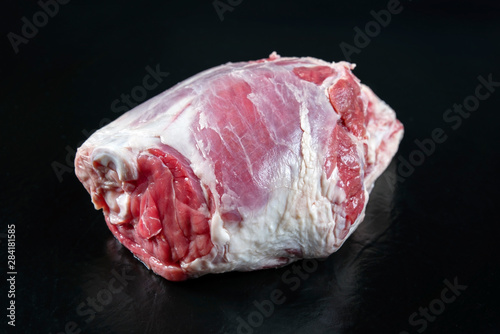 Traditional raw haunch of lamb as top view on a slate slab with copy space photo