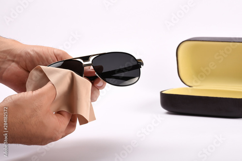 Male hands cleaning sunglasses with microfiber cloth