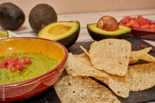 Guacamole prepared and ingredients on white table