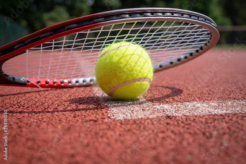 Detail of tennis rocket over ball on court surface © NetPix