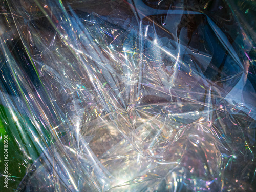 Crumpled transparent plastic film on a colorful background on a sunny day. Abstract background