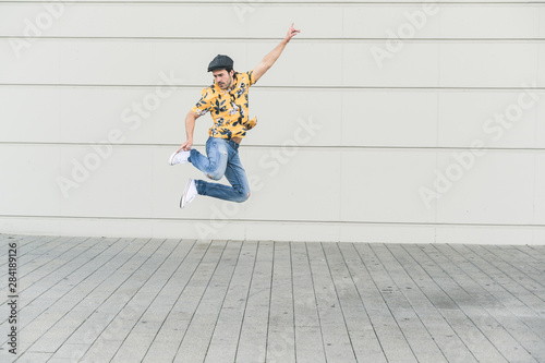 Young man wearing flat hat and aloha shirt, jumping for joy photo