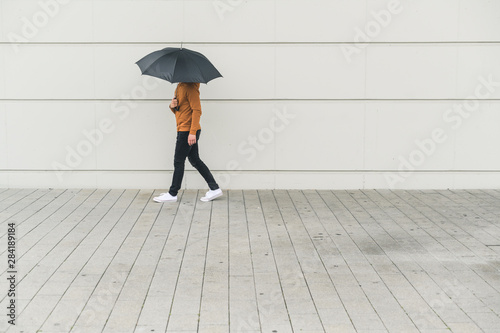 Young man with umbrella walking in the street photo