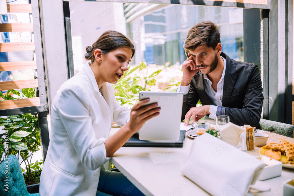 Two business partners discussing working plans while using tablet pc in cafe bar Two business partners discussing working plans while using tablet pc in cafe bar
