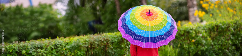 Boy holding colourful umbrella under rain in summer - obrazy, fototapety, plakaty 