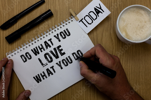 Text sign showing Do What You Love What You Do. Conceptual photo Make things that motivate yourself Passion Paperclip retain written notepad hand hold marker coffee black pen on woody desk photo