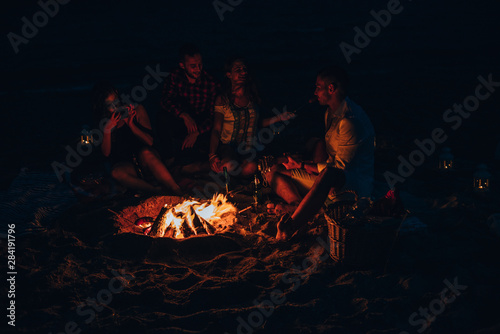 Happy friends having fun around bonfire