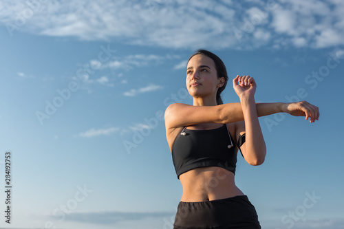 Slim athletic girl performs stretching exercises on the roof of an unfinished building, urban background.	 photo