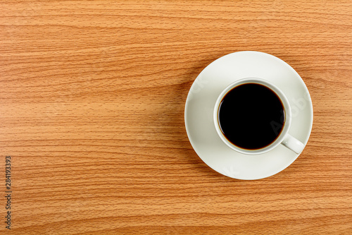 white ceramic coffee cup on wooden desk. - blank space for advertising text.