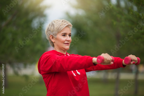 beautiful elderly woman with short haircut goes in for sports in the park