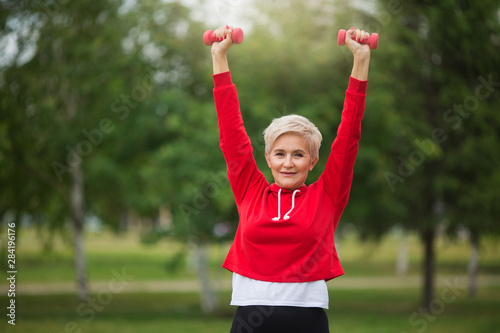 beautiful elderly woman with short haircut goes in for sports in the park