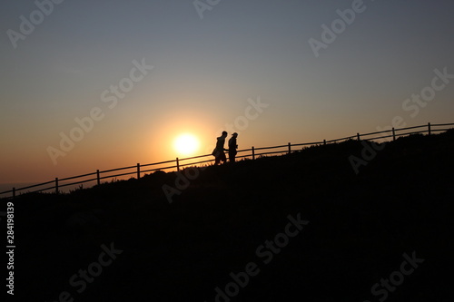 Silhouette of a couple climbing up at sunset