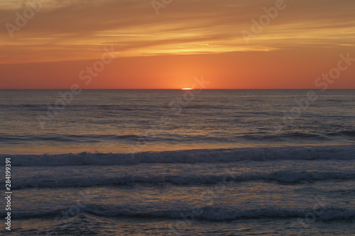  Red-violet sunset over the Atlantic ocean. White disc of the sun over the red sea at sunset. Natural bright background is suitable for postcard, touristic guide, greeting card.