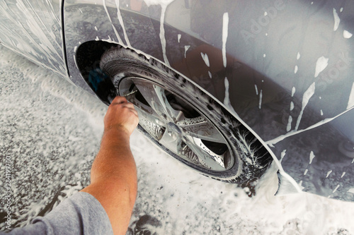Gomel, Belarus - August 4, 2019: A bearded man with glasses washes a silver Hyundai Elantra GLS car. Wheels from a car photo