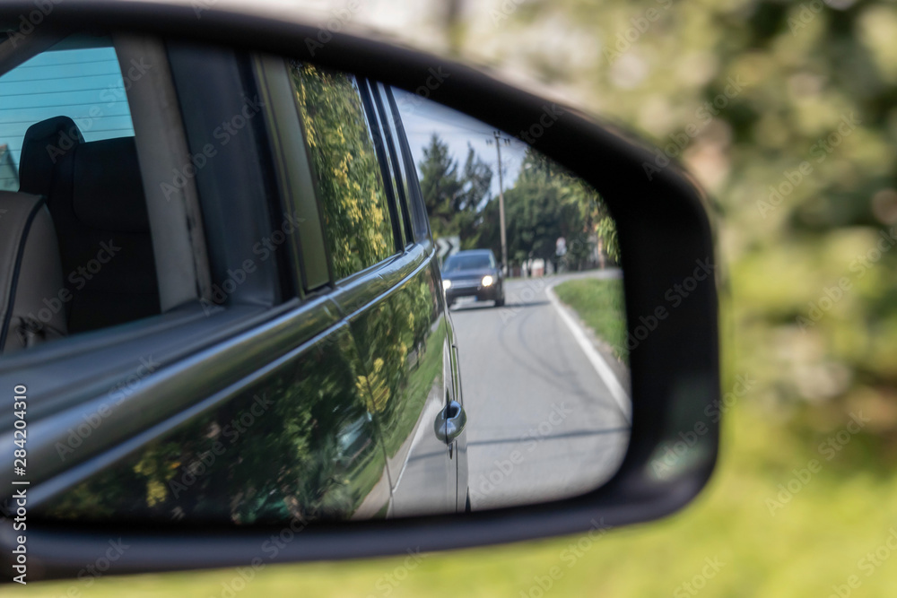 Side view mirror of a car, tracking traffic on the road