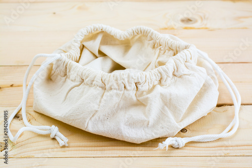 Empty opened canvas bag on the ties for food on a natural wooden background. Zero Waste Concept