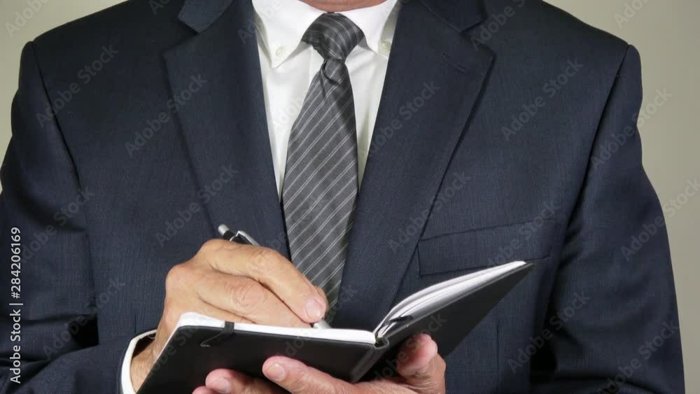 Closeup of a businessman taking notes in a small black notebook. Closeup of a businessman taking notes in a small black notebook.