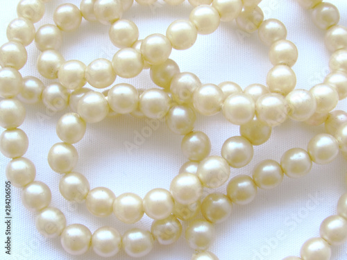 Delicate light natural small pearl long beads on a white background.