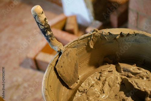 Builder builds a brick stove, builder tools. Trowel with a solution in a bucket