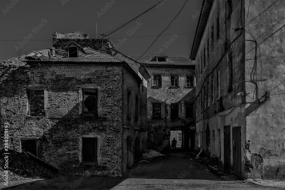 The yard of an abandoned old brick building at night in the moonlight.