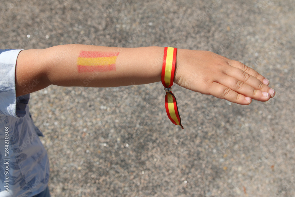 brazo de un niño con pulsera de los colores de la bandera de españa y  bandera pintada en el brazo Stock Photo | Adobe Stock