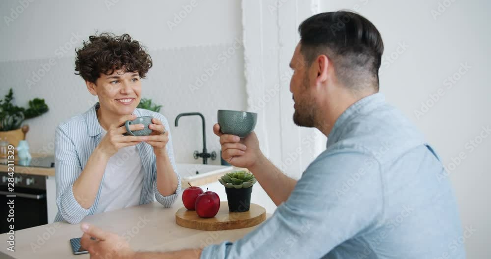 Girl and guy happy family are talking drinking coffee laughing at home sitting together at kitchen table. Modern lifestyle, communication and relations concept. Girl and guy happy family are talking drinking coffee laughing at home sitting together at kitchen table. Modern lifestyle, communication and relations concept.