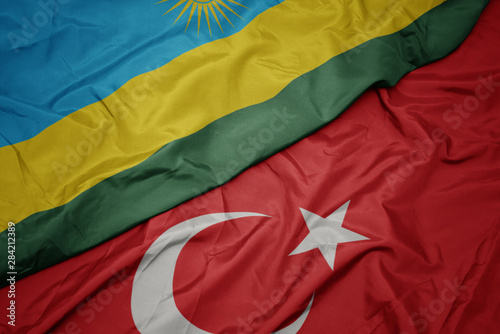 waving colorful flag of turkey and national flag of rwanda.