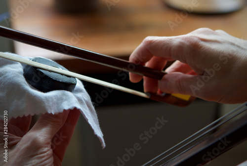 Caucasian woman applying cello rosin to bow