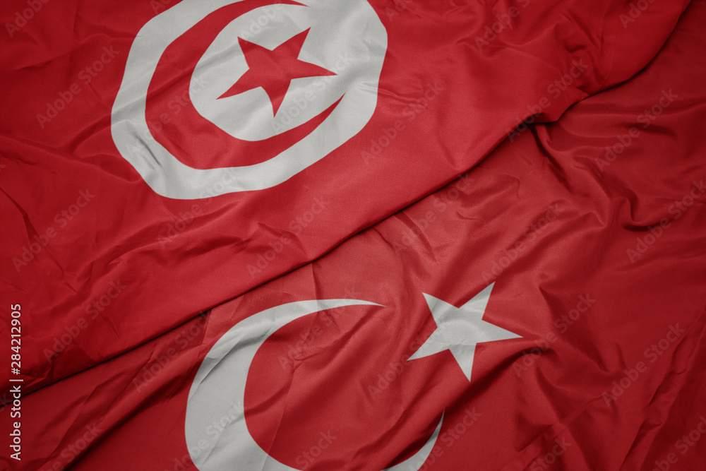 waving colorful flag of turkey and national flag of tunisia.