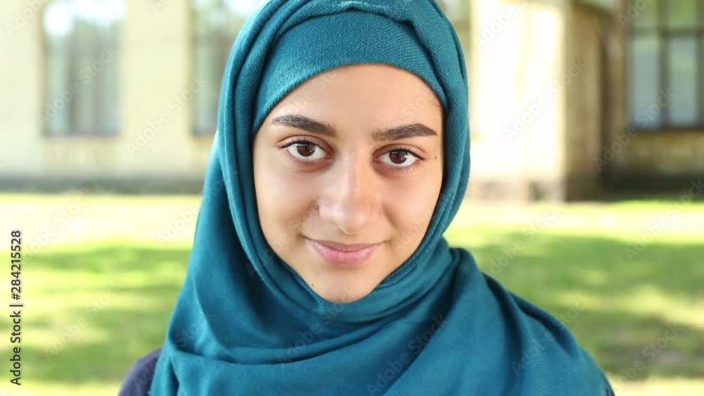 Portrait of a smiling muslim girl in hijab. Close-up face of a happy Arabic young woman with beautiful eyes.