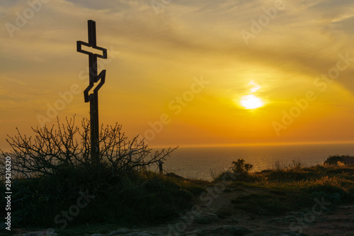 Cross on a cliff with a beautiful sunset sky in the background