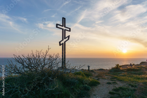 Cross on a cliff with a beautiful sunset sky in the background