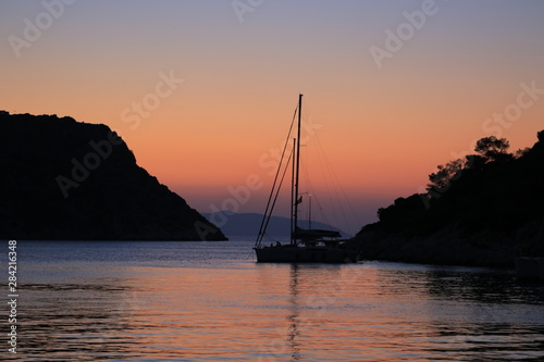Sailing yacht at sunset anchored near the island photo