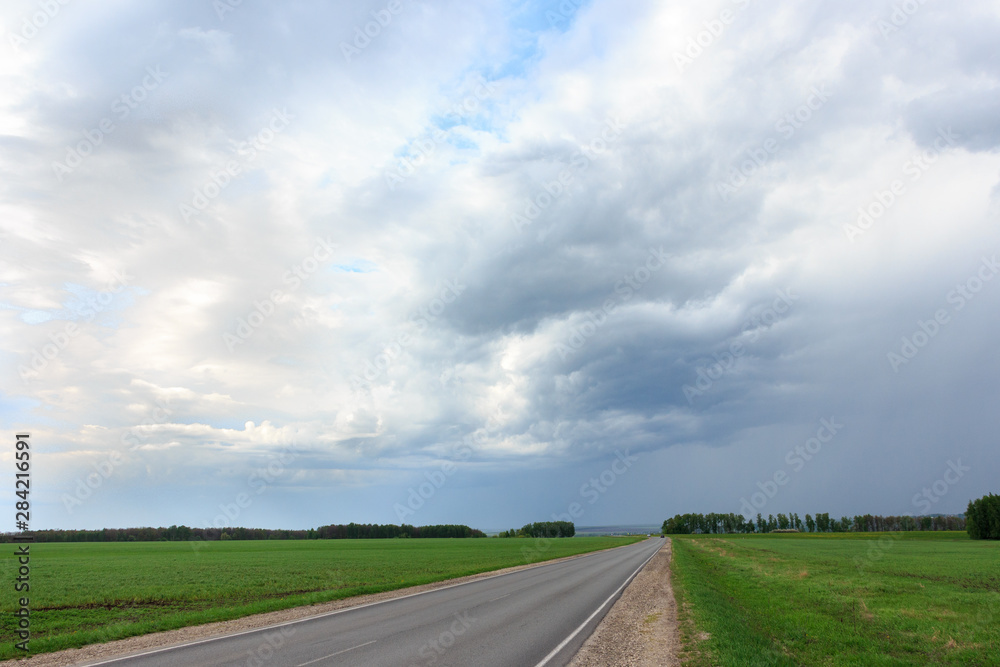 The road in the Russian village with a cloudy sky before a thunderstorm.