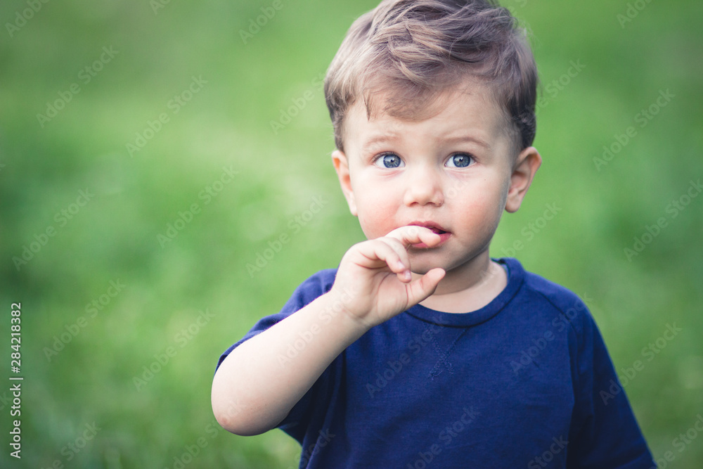 Blond boy in blue t-shirt with beautiful blue eyes looking at something Blond boy in blue t-shirt with beautiful blue eyes looking at something