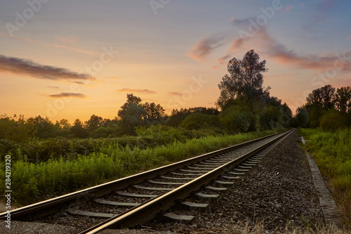 Railroad track in countryside during sunset in summer. Transportation concept, travel background.