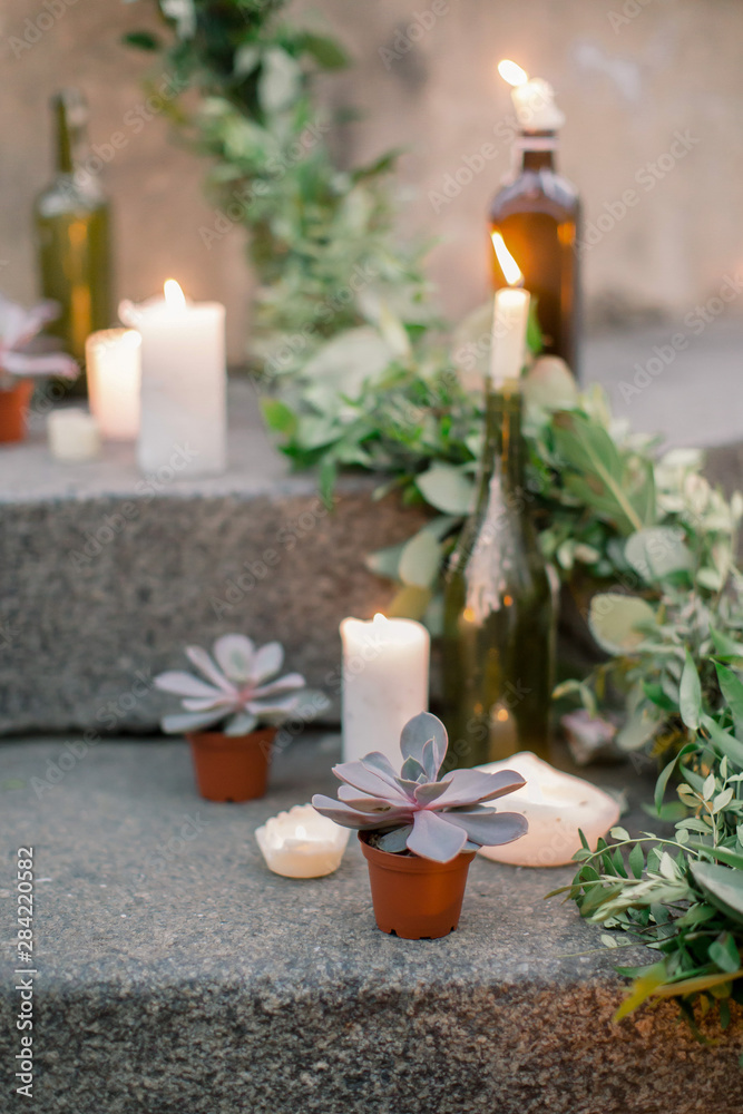 Wedding ceremony decor, decorated stone stairs with white burning candles and fresh greenery, flowers and succulents