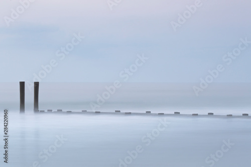 Lonely pier in the ocean at sunrise with long exposure