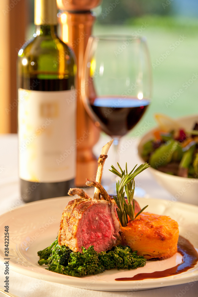Lamb chops on a white plate with red wine.