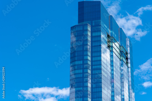 Cloudy sky reflecting off blue office window glass on a sky scraper in Boston