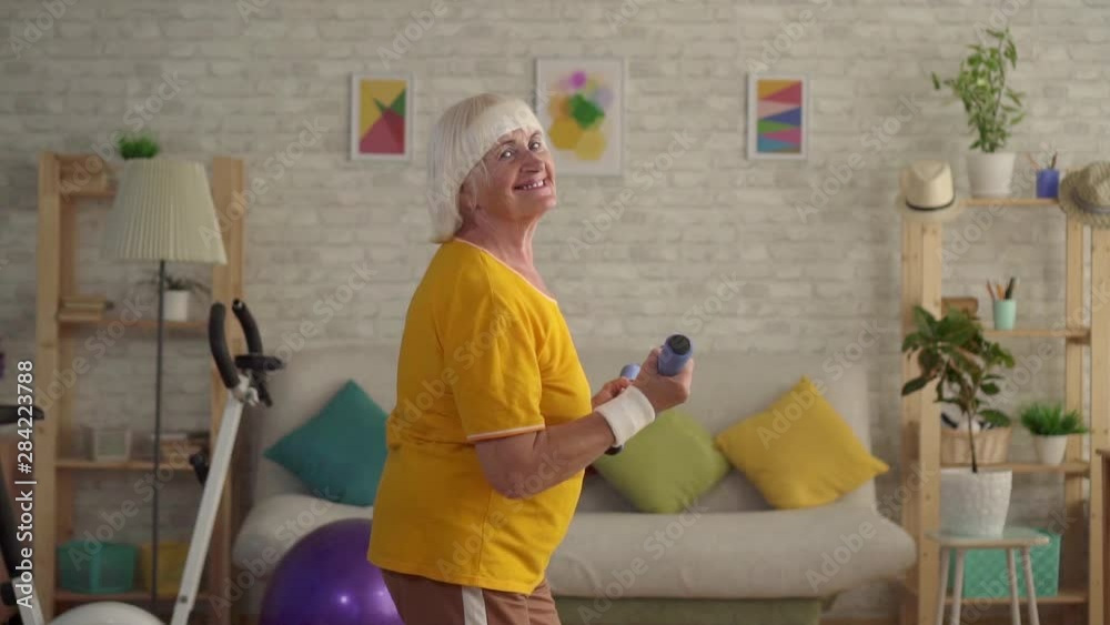 positive fitness senior woman does sports exercises and looks at the camera positive fitness senior woman does sports exercises and looks at the camera
