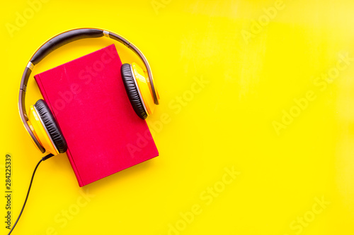 listen to audio books with headphone on yellow background flatlay mock up