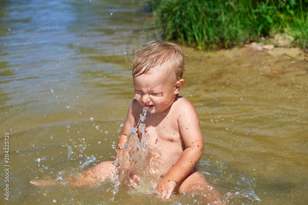 Toddler splashing water near the shore Toddler splashing water near the shore