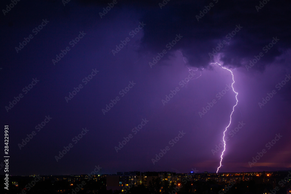 Lightning strikes storm over city purple light.