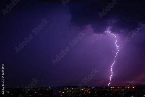 Lightning strikes storm over city purple light.