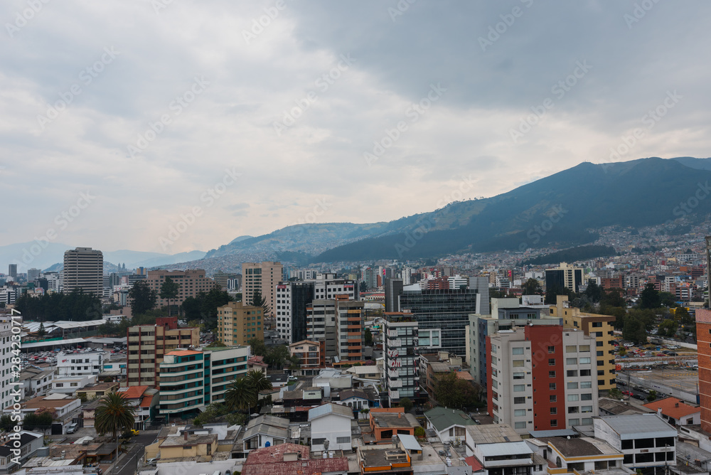 Atardecer de ciudad sudamerica en Quito Ecuador con edificios y montañas de fondo con cielo nublado