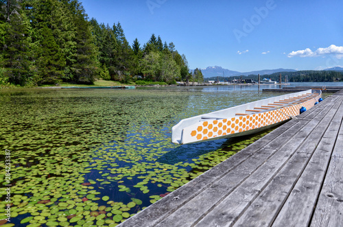 Canvas Print beautiful long wooden white boat at a wooden pier on a picturesque Sproat Lake o