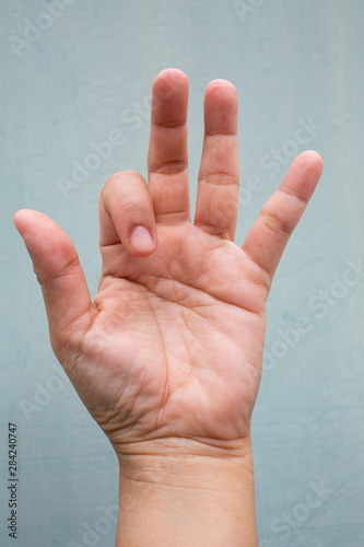 Trigger Finger lock on index finger of woman's front left hand, Suffering from pain, On Blue-grey colour background, Close up & Macro shot, Office syndrome, Health care concept